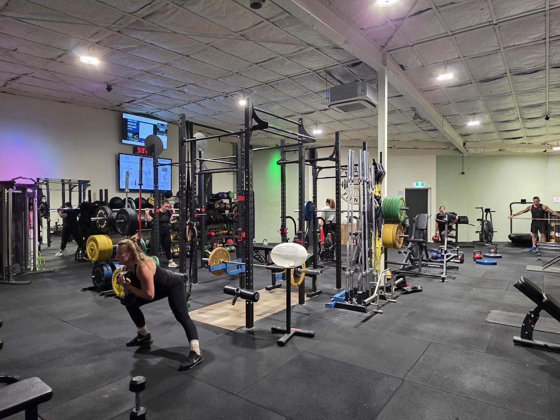 A-New Fitness gym floor with squat racks, weights and members training